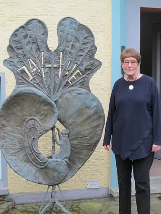 Besonders bei den Predigten in den Altenheimen arbeitet Prädikantin Gabriele Bieling viel mit Bildern. Hier steht sie vor der Galerie Rika Unger neben der Bronzeplastik „Geheimnis des Hörens“ von Rika Unger. Foto: Felder 